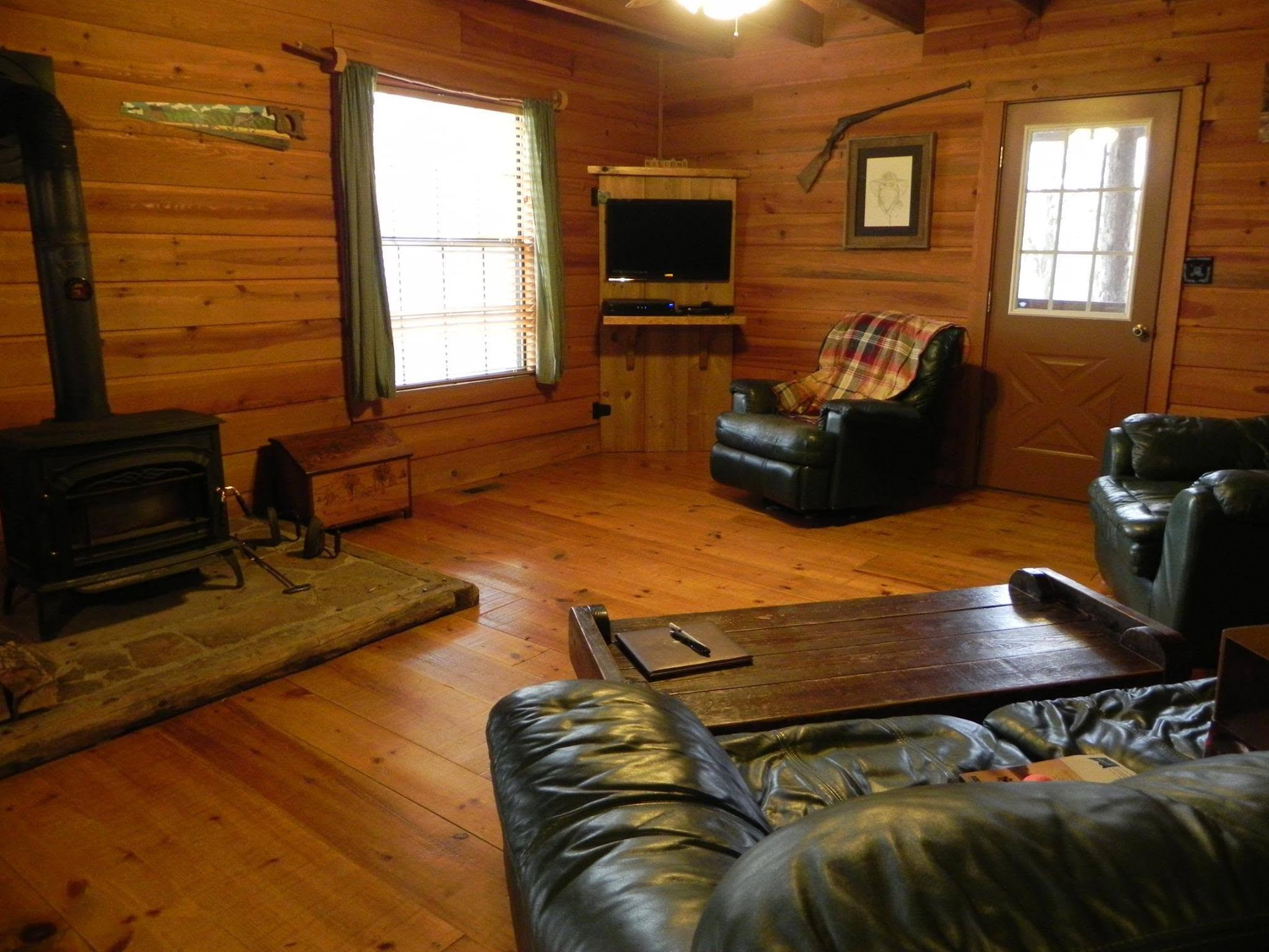 Living room inside Kindling Trail Cabin with wood-paneled walls, fireplace, and seating